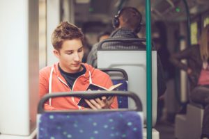 Teenage boy reading a book on the tram