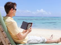 handsome man at the beach reading his electronic reader