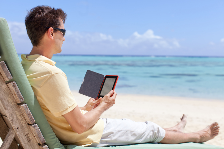 handsome man at the beach reading his electronic reader